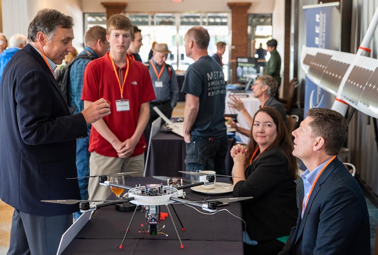 Attendees and exhibitors chat over a drone on display